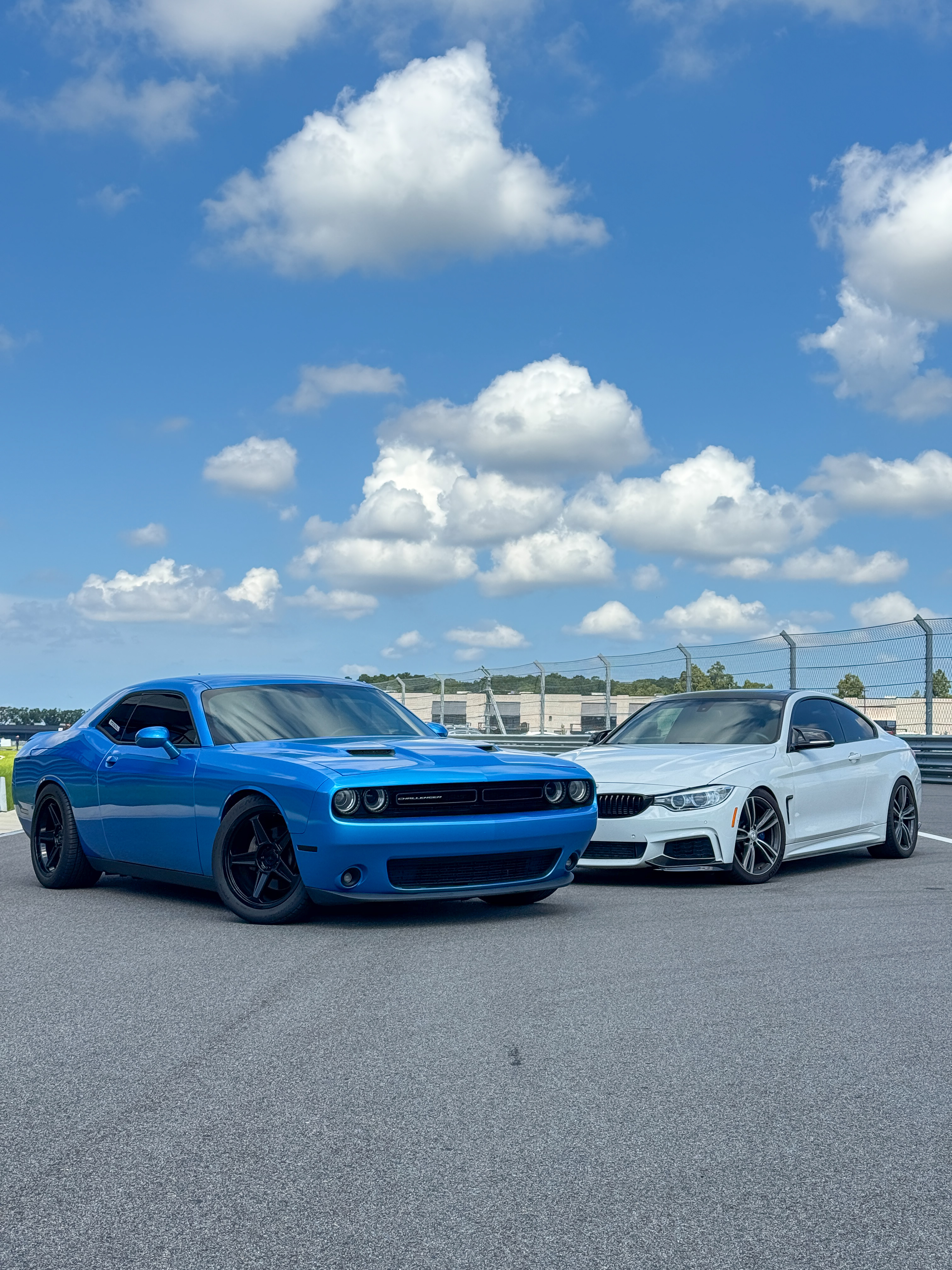 Blue Dodge Challenger and white BMW coupe at the track